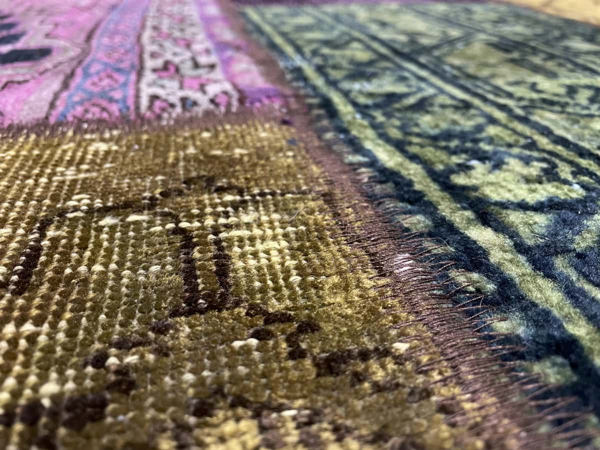 alfombra persa de estilo patchwork en dimensiones 207 centímetros de largo por 152 centímetros de ancho con colores principalmente verde y morado — Primer plano de la textura
