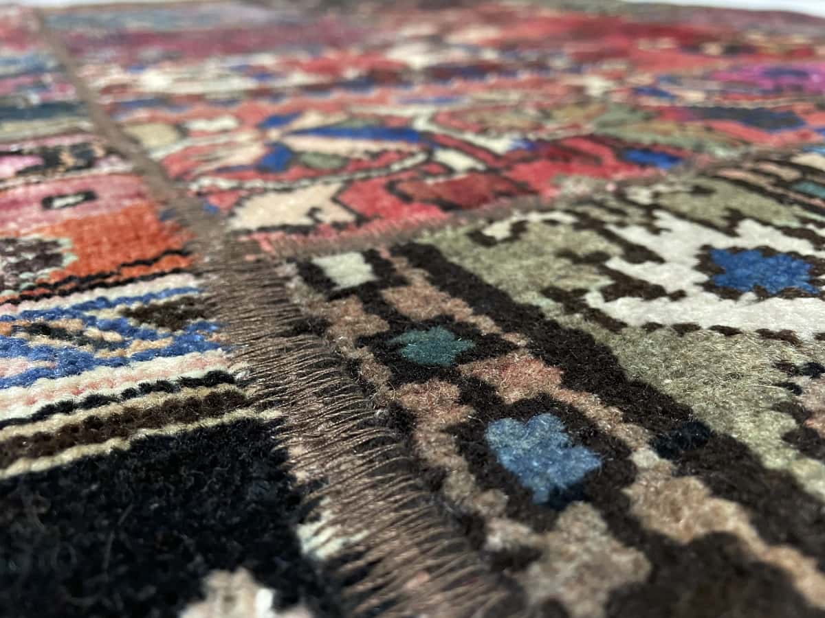 Persian rug of Patchwork style in dimensions 204 centimeters length by 151 centimeters width with mainly red colors — Texture close-up