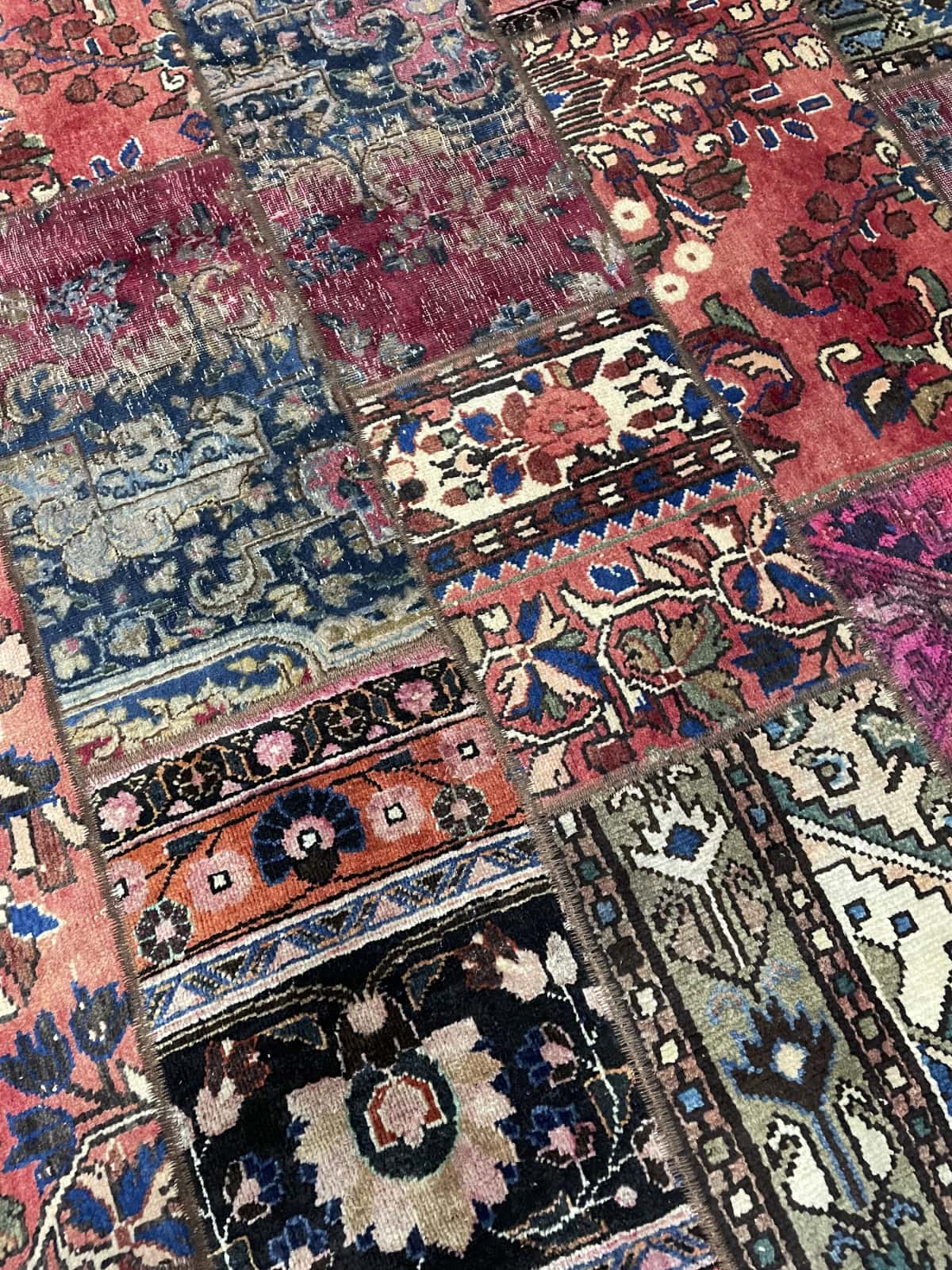 Persian rug of Patchwork style in dimensions 204 centimeters length by 151 centimeters width with mainly red colors — Texture close-up