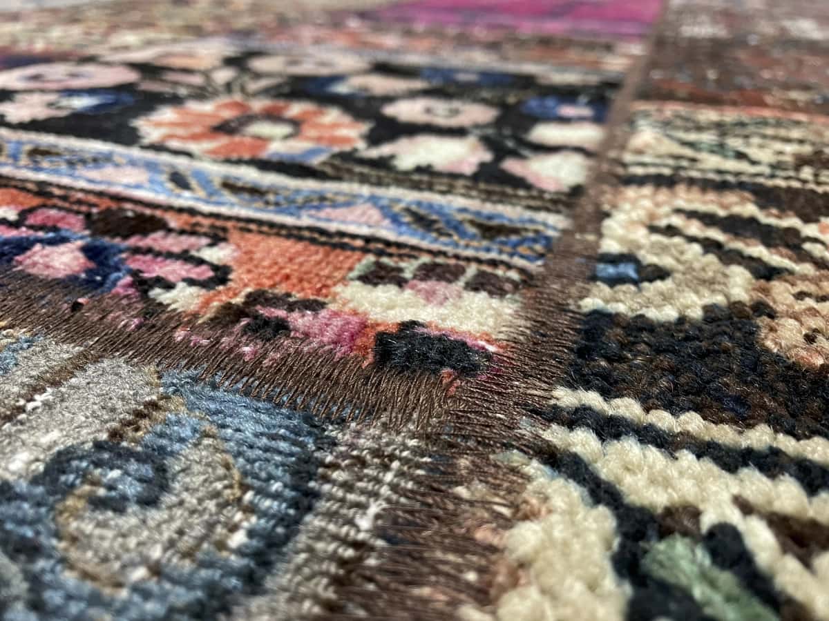 alfombra persa de estilo patchwork en dimensiones 206 centímetros de largo por 152 centímetros de ancho con colores principalmente rojo y morado — Primer plano de la textura