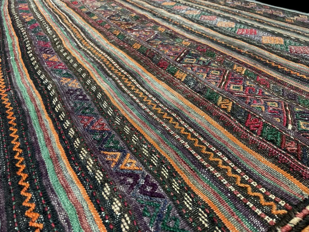 Persian rug of Sumak style in dimensions 156 centimeters length by 113 centimeters width with mainly purple and brown colors — Texture close-up