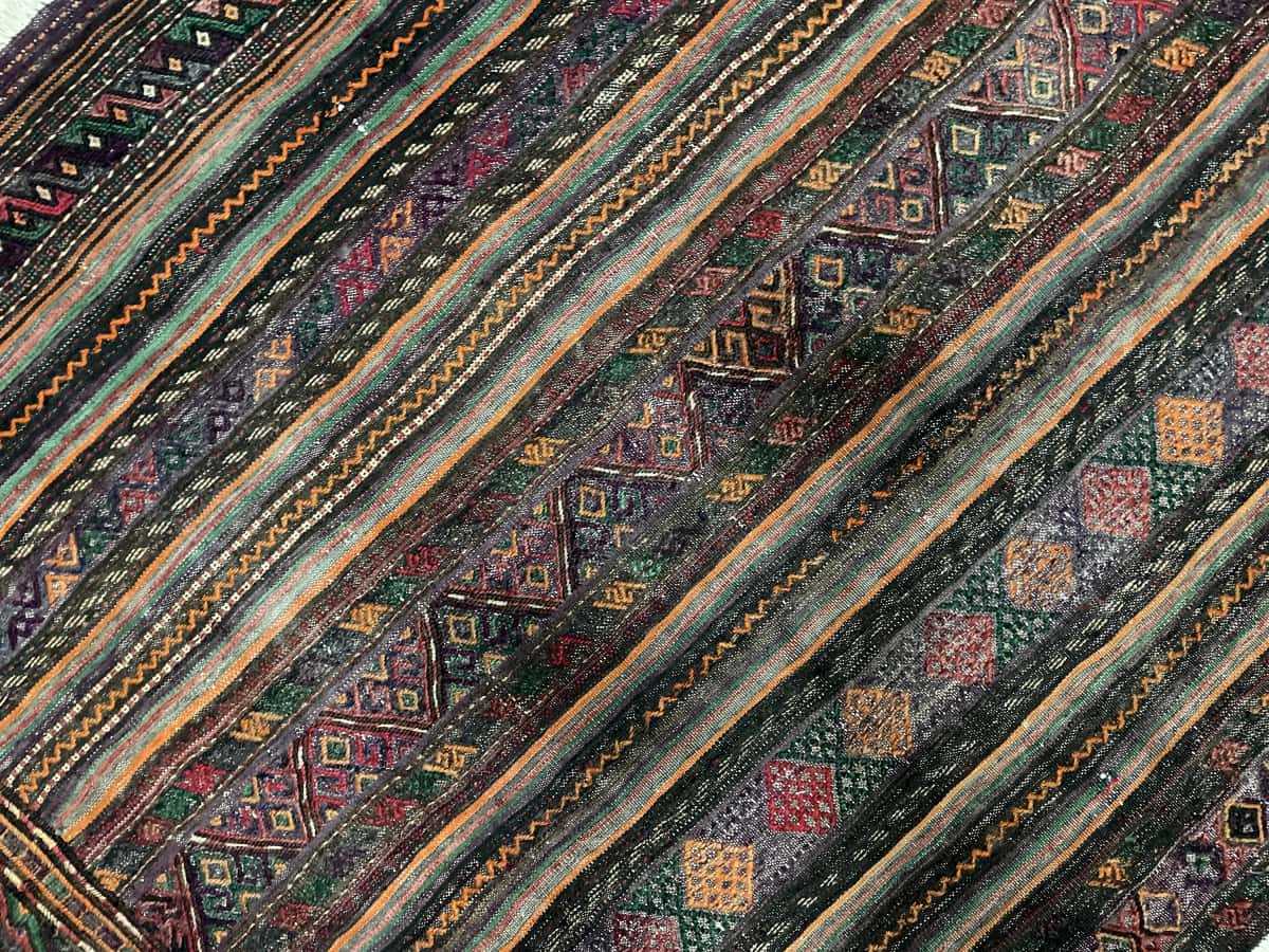 Persian rug of Sumak style in dimensions 156 centimeters length by 113 centimeters width with mainly purple and brown colors — Texture close-up