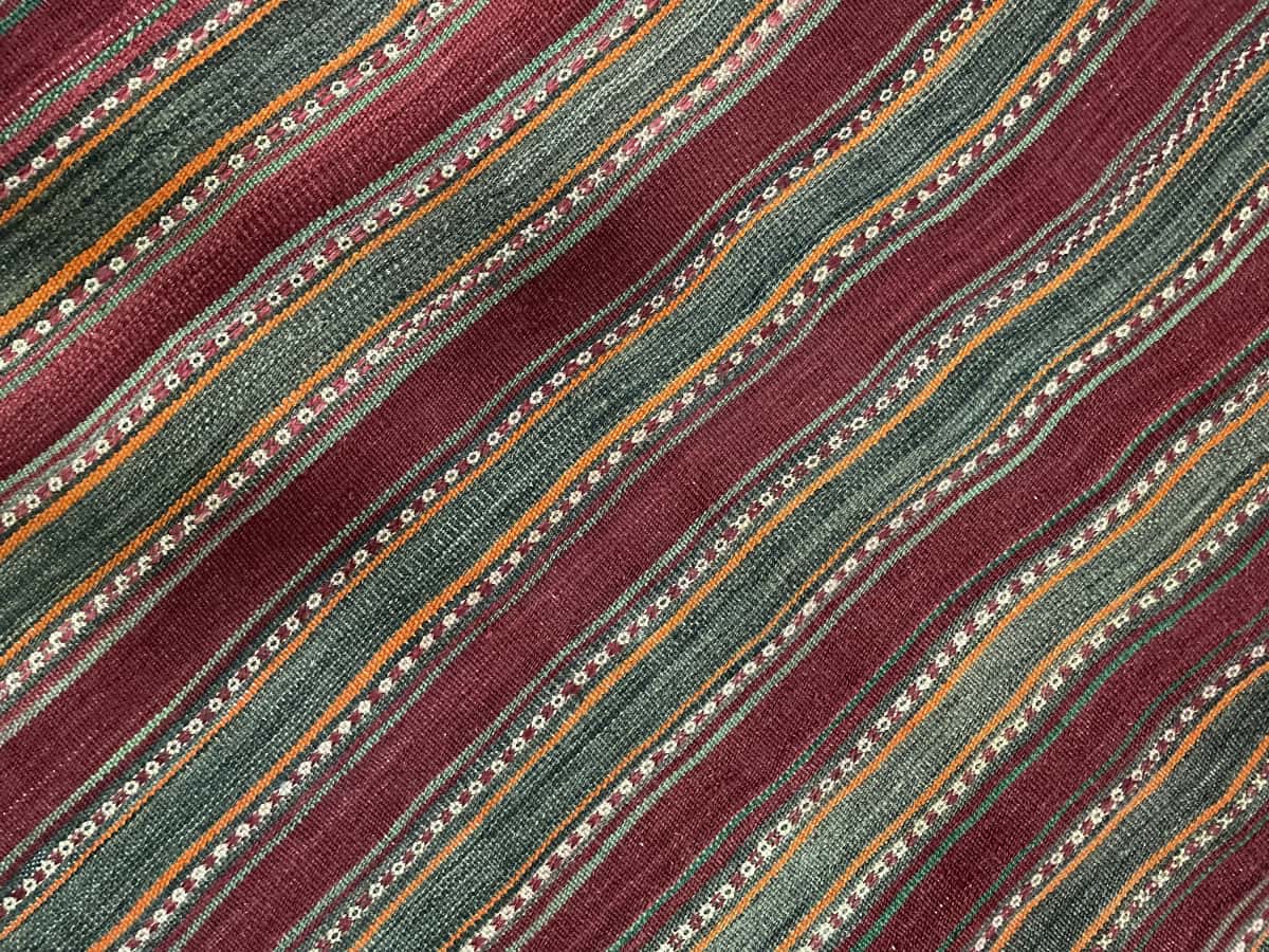 Persian rug of Sumak style in dimensions 177 centimeters length by 131 centimeters width with mainly red and orange colors — Texture close-up