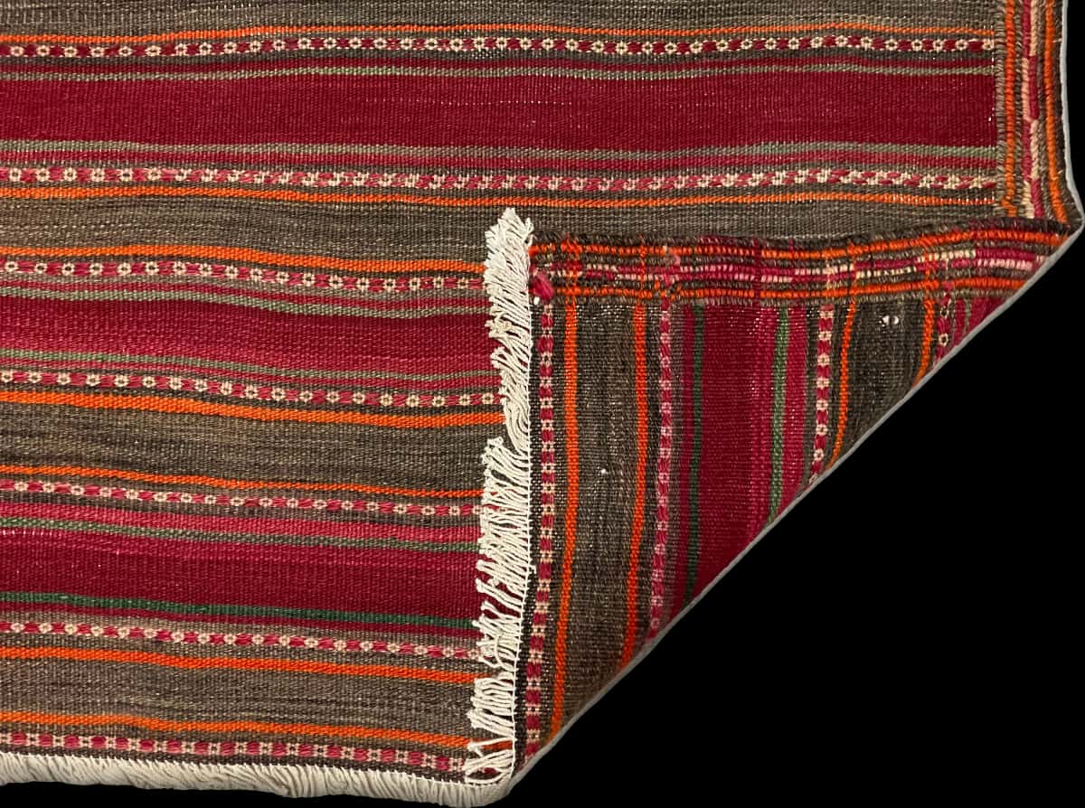 persischer Teppich im Sumak Stil in den Maßen 177 Zentimeter Länge mal 131 Zentimeter Breite mit überwiegend rot und orange Farben — Gefaltet
