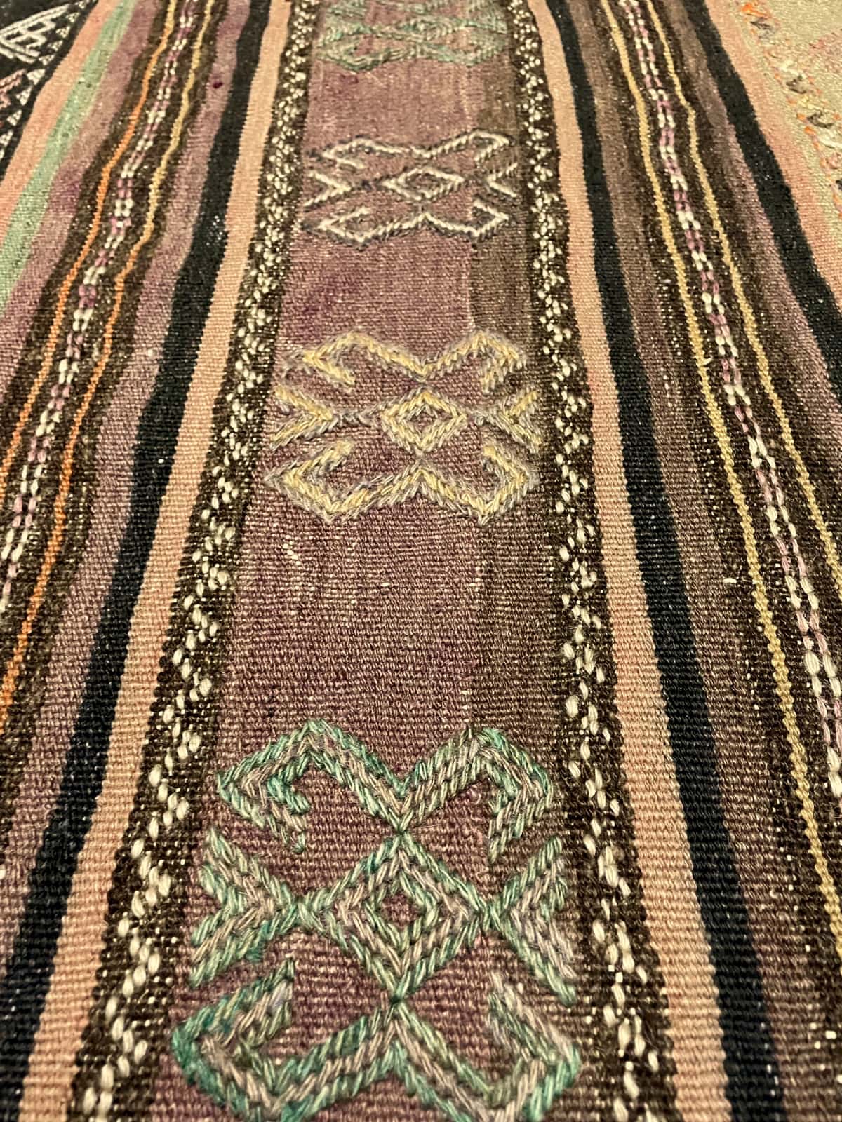 Persian rug of Sumak style in dimensions 254 centimeters length by 145 centimeters width with mainly purple colors — Texture close-up