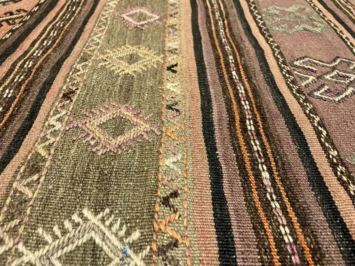 Persian rug of Sumak style in dimensions 254 centimeters length by 145 centimeters width with mainly purple colors — Texture close-up
