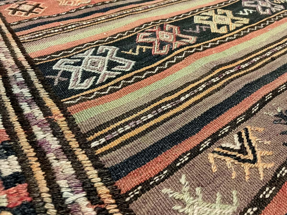 Persian rug of Sumak Kilim style in dimensions 228 centimeters length by 151 centimeters width with mainly brown colors — Texture close-up
