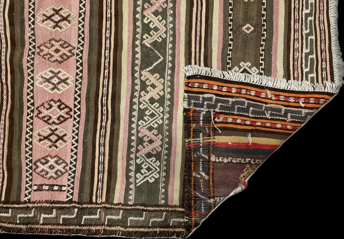 alfombra persa de estilo sumak en dimensiones 125 centímetros de largo por 120 centímetros de ancho con colores principalmente beige y rosa — Plegada