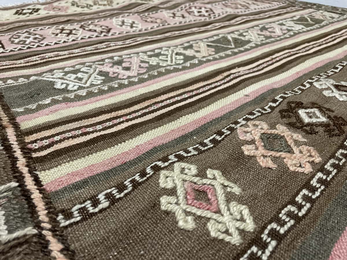 alfombra persa de estilo sumak en dimensiones 125 centímetros de largo por 120 centímetros de ancho con colores principalmente beige y rosa — Primer plano de la textura