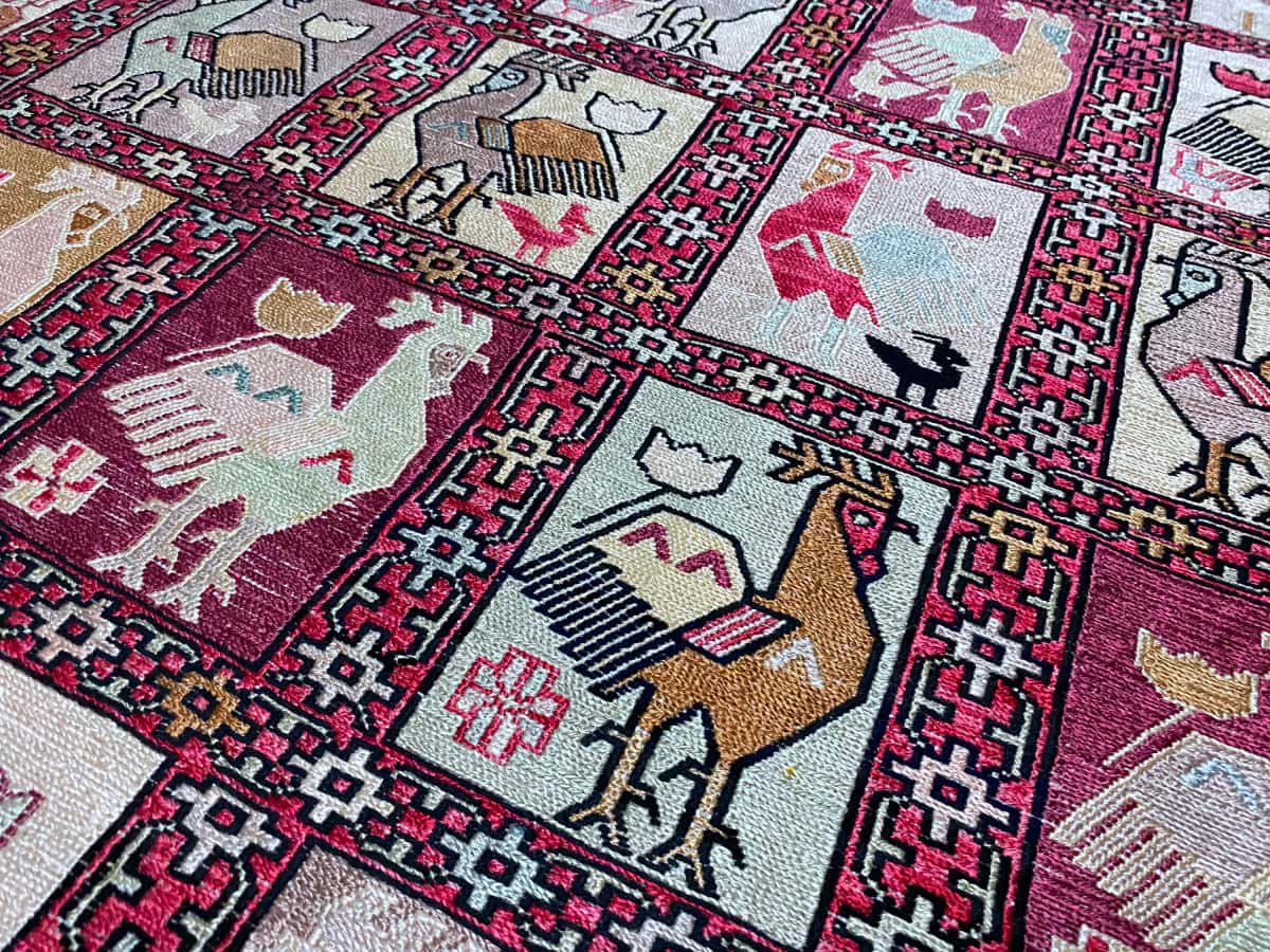 Persian rug in dimensions 188 centimeters length by 118 centimeters width with mainly beige and red colors — Texture close-up