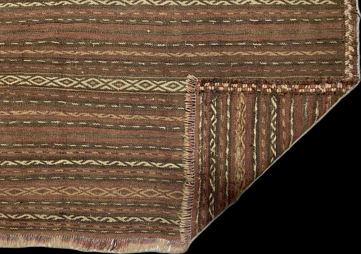 alfombra persa de estilo sumak en dimensiones 290 centímetros de largo por 153 centímetros de ancho con colores principalmente rojo y marrón — Plegada