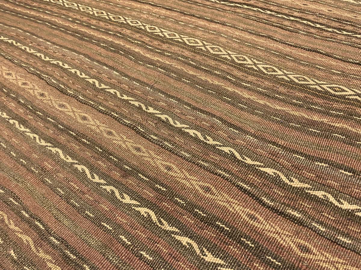 alfombra persa de estilo sumak en dimensiones 290 centímetros de largo por 153 centímetros de ancho con colores principalmente rojo y marrón — Primer plano de la textura