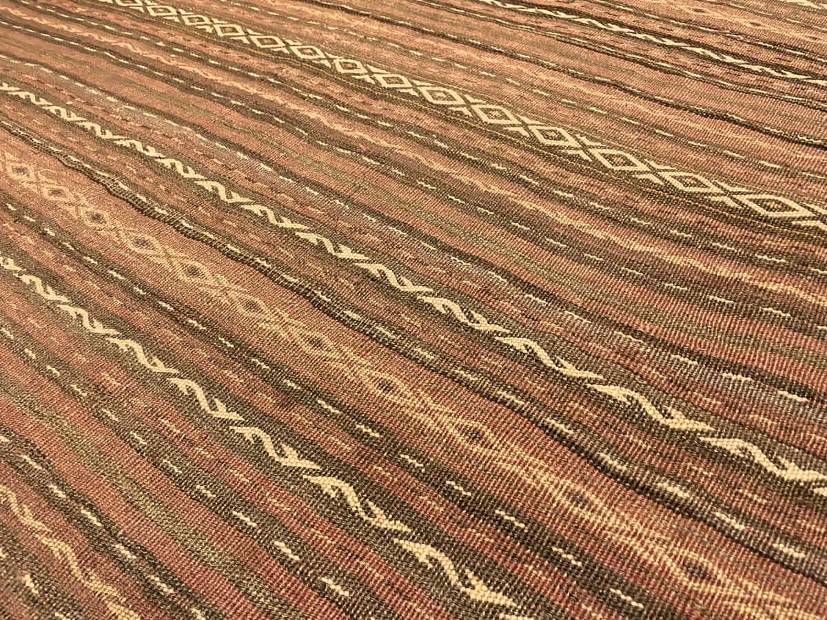 Persian rug of Sumak style in dimensions 290 centimeters length by 153 centimeters width with mainly red and brown colors — Texture close-up