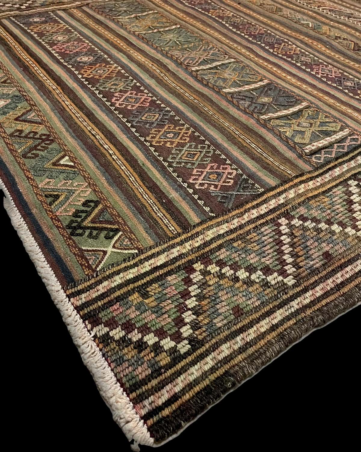 persischer Teppich im Sumak Stil in den Maßen 206 Zentimeter Länge mal 141 Zentimeter Breite mit überwiegend grün und lila Farben — Ecke & Kante