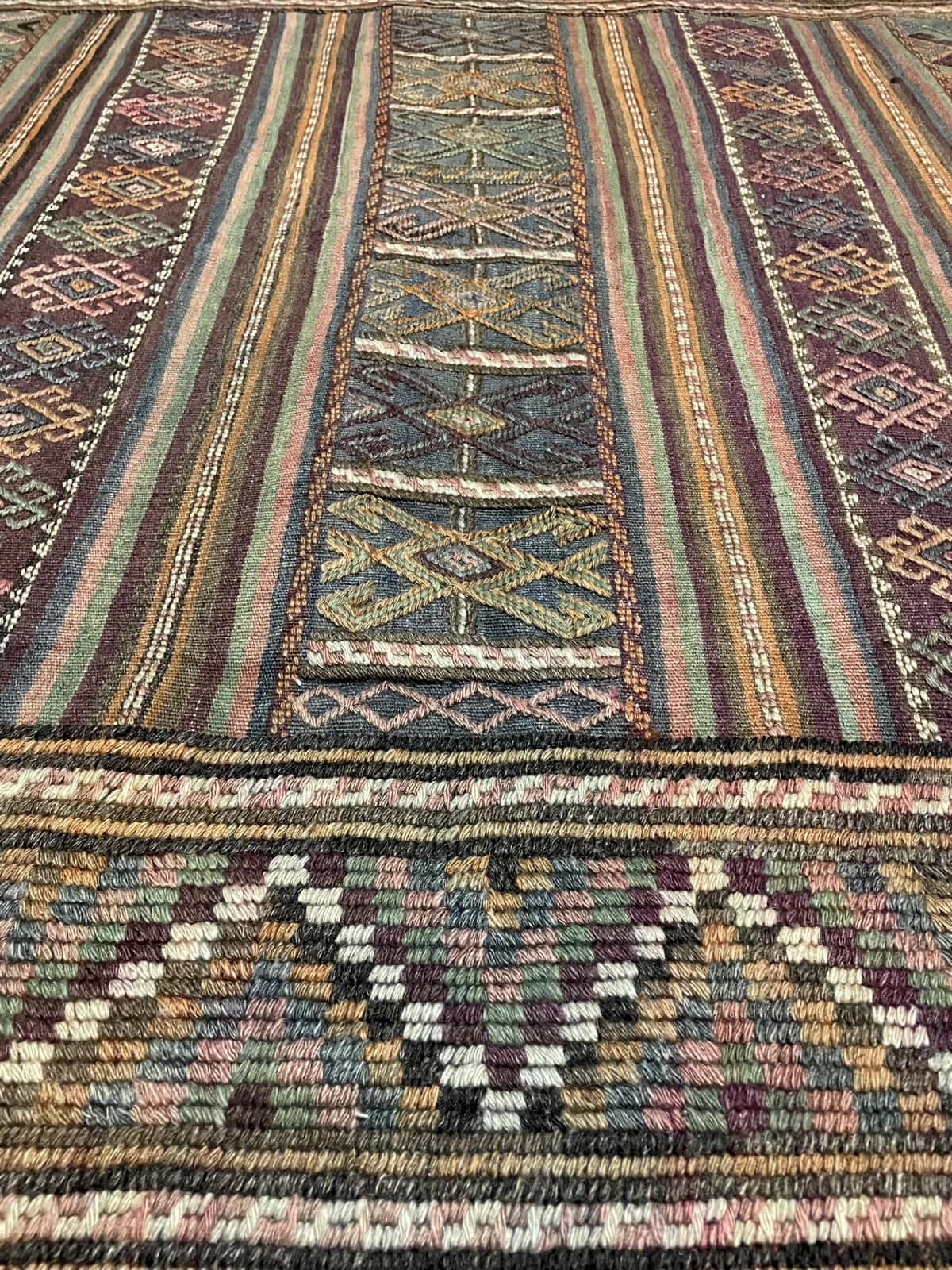 persischer Teppich im Kelim-Sumak Stil in den Maßen 206 Zentimeter Länge mal 141 Zentimeter Breite mit überwiegend Grün und Lila Farben — Nahaufnahme der Textur