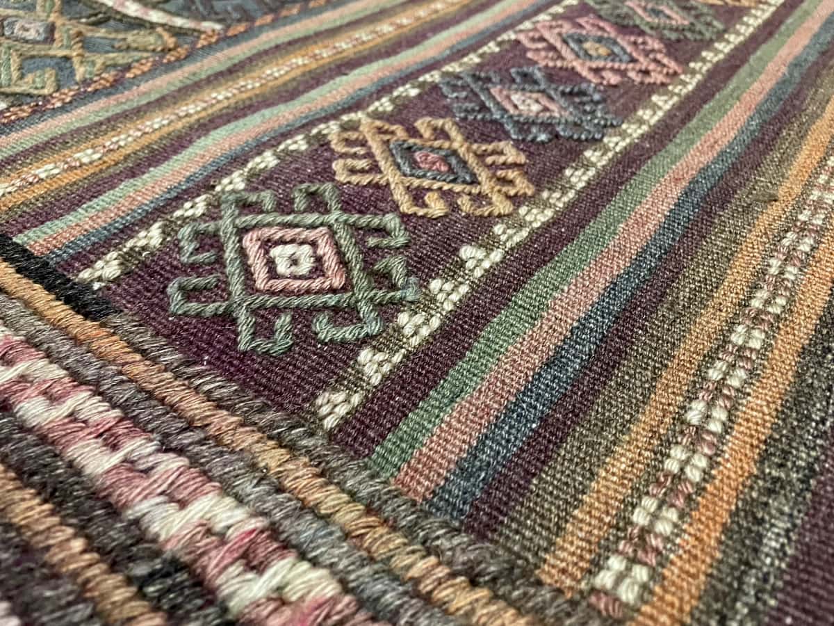 persischer Teppich im Kelim-Sumak Stil in den Maßen 206 Zentimeter Länge mal 141 Zentimeter Breite mit überwiegend Grün und Lila Farben — Nahaufnahme der Textur