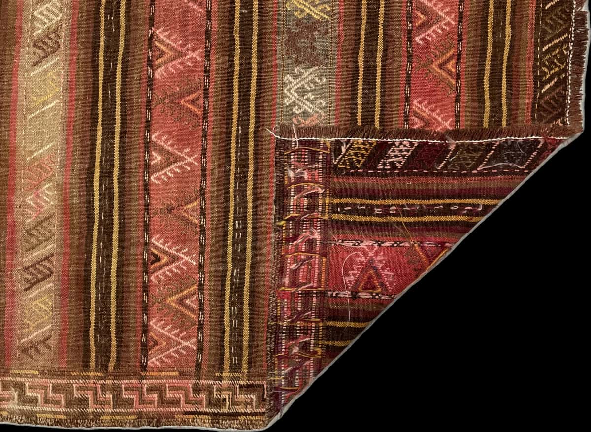 alfombra persa de estilo sumak en dimensiones 207 centímetros de largo por 135 centímetros de ancho con colores principalmente amarillo y rosa — Plegada