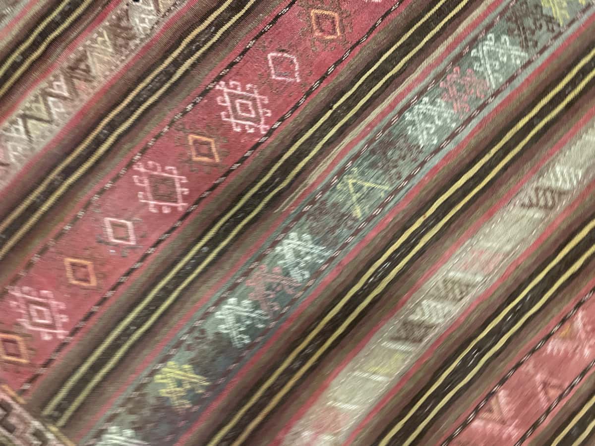 alfombra persa de estilo sumak en dimensiones 207 centímetros de largo por 135 centímetros de ancho con colores principalmente amarillo y rosa — Primer plano de la textura