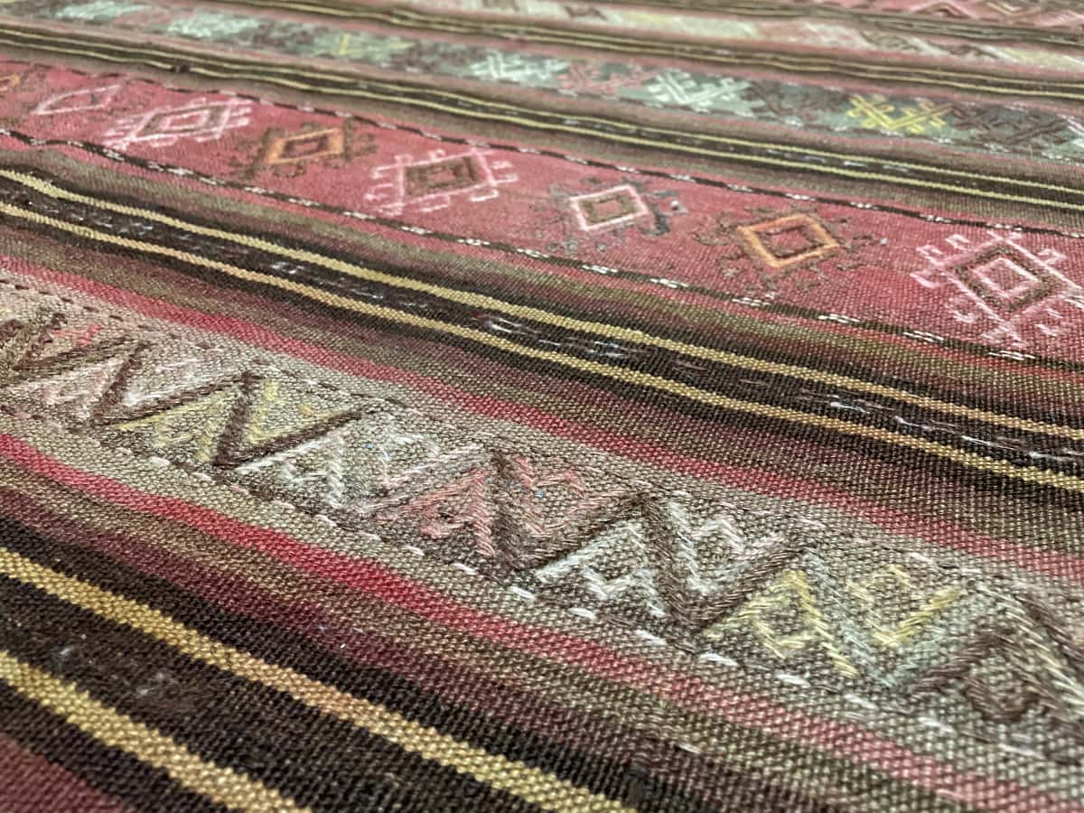 alfombra persa de estilo sumak en dimensiones 207 centímetros de largo por 135 centímetros de ancho con colores principalmente amarillo y rosa — Primer plano de la textura
