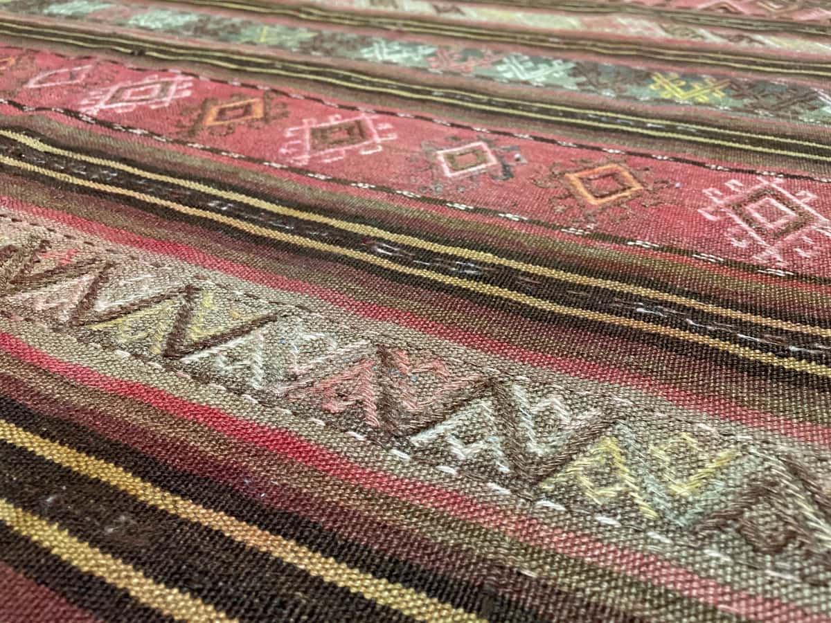 persischer Teppich im Sumak Stil in den Maßen 207 Zentimeter Länge mal 135 Zentimeter Breite mit überwiegend gelb und rosa Farben — Nahaufnahme der Textur
