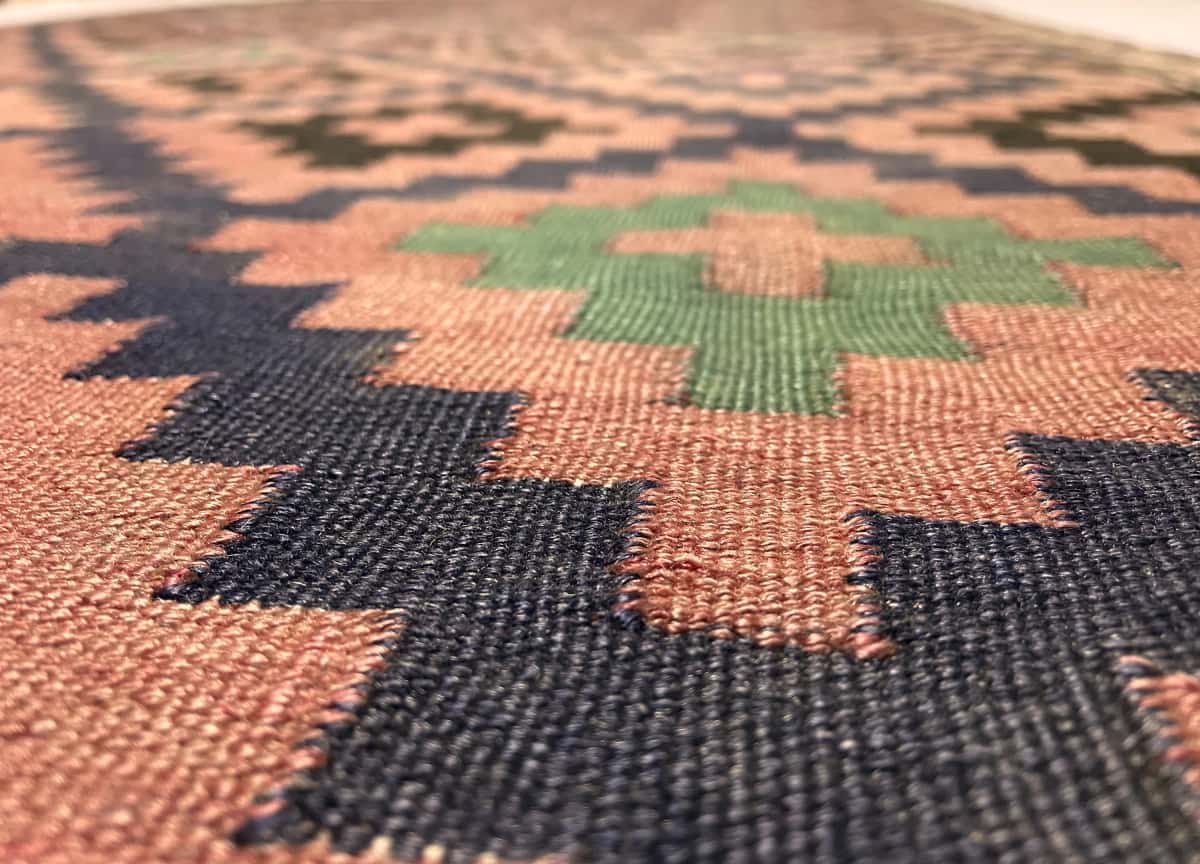 alfombra persa de estilo sumak en dimensiones 270 centímetros de largo por 135 centímetros de ancho con colores principalmente rojo y negro — Primer plano de la textura