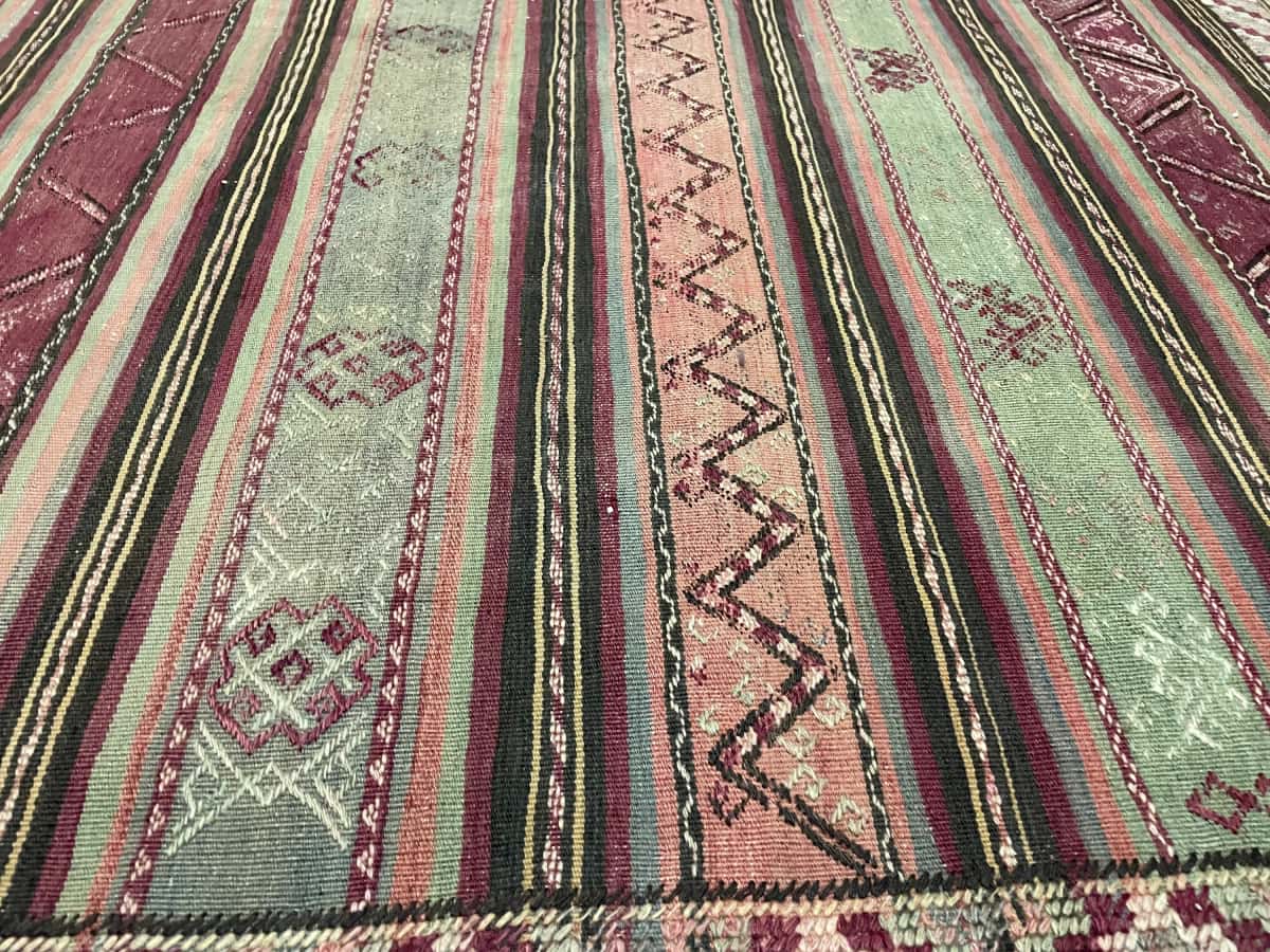 Persian rug of Sumak Kilim style in dimensions 200 centimeters length by 163 centimeters width with mainly green and purple colors — Texture close-up