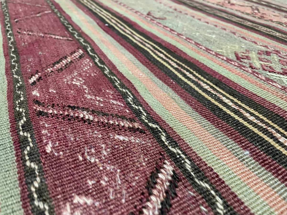 Persian rug of Sumak Kilim style in dimensions 200 centimeters length by 163 centimeters width with mainly green and purple colors — Texture close-up