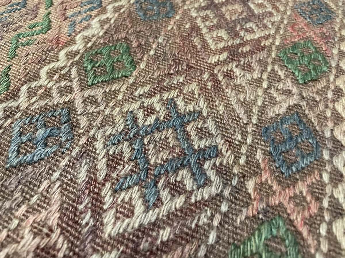 Persian rug of Sumak Kilim style in dimensions 233 centimeters length by 150 centimeters width with mainly brown colors — Texture close-up