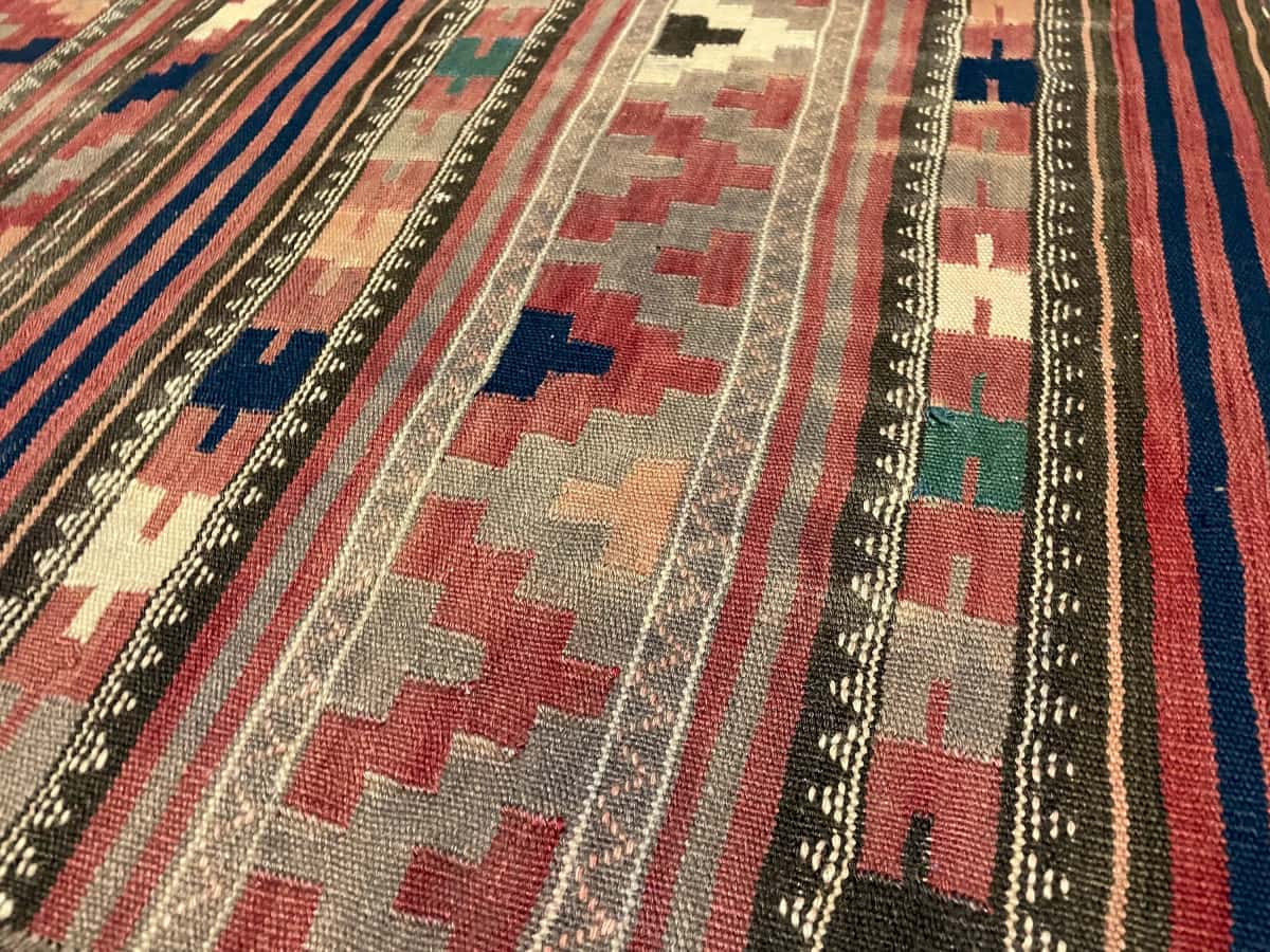 Persian rug of Sumak style in dimensions 268 centimeters length by 130 centimeters width with mainly red colors — Texture close-up