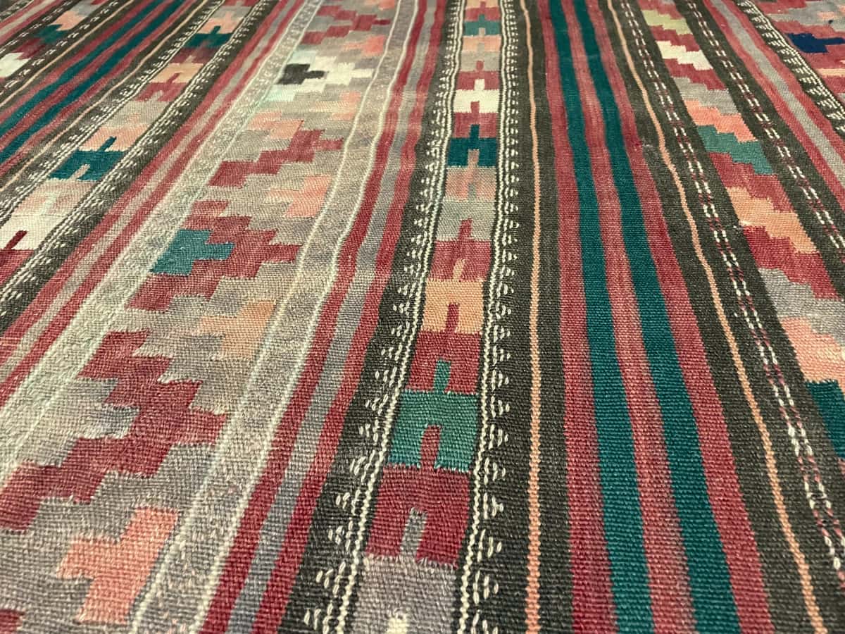 Persian rug of Sumak style in dimensions 268 centimeters length by 130 centimeters width with mainly red colors — Texture close-up