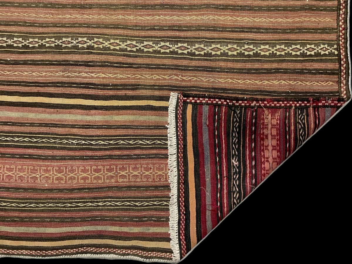 alfombra persa de estilo sumak en dimensiones 200 centímetros de largo por 150 centímetros de ancho con colores principalmente marrón — Plegada