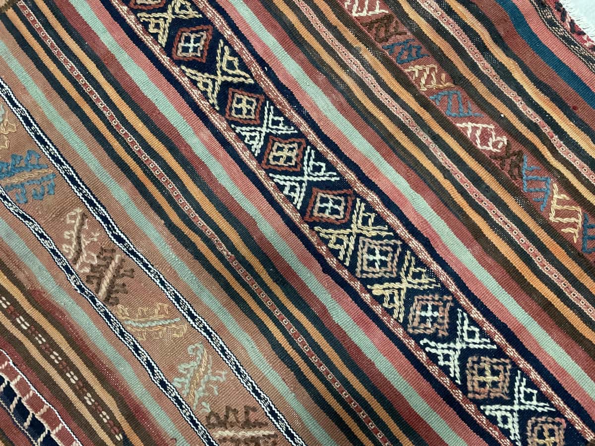 Persian rug of Sumak style in dimensions 128 centimeters length by 113 centimeters width with mainly brown and red colors — Texture close-up