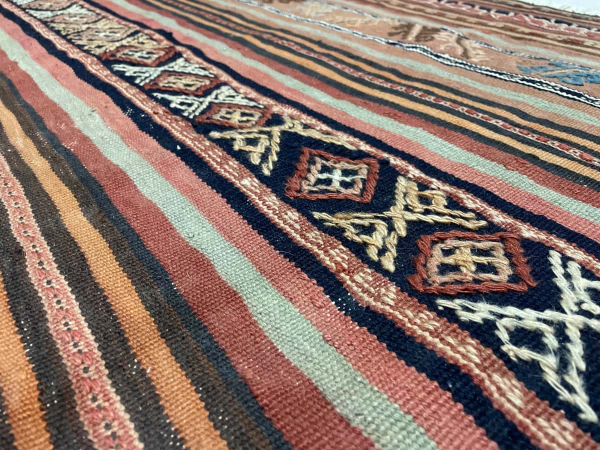 Persian rug of Sumak style in dimensions 128 centimeters length by 113 centimeters width with mainly brown and red colors — Texture close-up