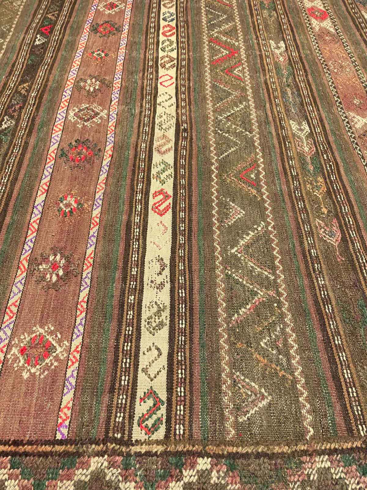 Persian rug of Sumak style in dimensions 260 centimeters length by 145 centimeters width with mainly brown and green colors — Texture close-up