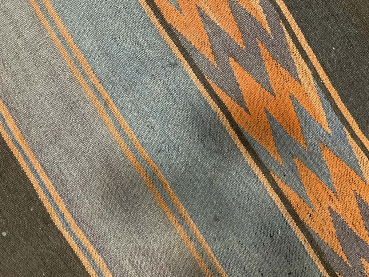 alfombra persa de estilo kilim en dimensiones 137 centímetros de largo por 115 centímetros de ancho con colores principalmente naranja y marrón — Primer plano de la textura