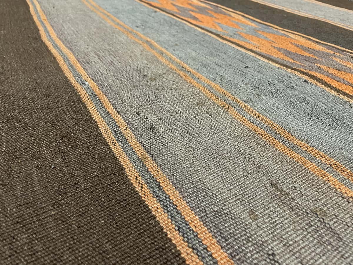 alfombra persa de estilo kilim en dimensiones 137 centímetros de largo por 115 centímetros de ancho con colores principalmente naranja y marrón — Primer plano de la textura