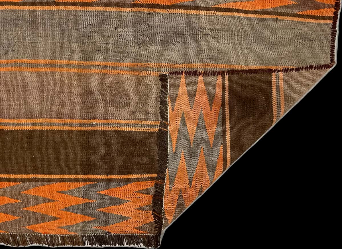 persischer Teppich im Kilim Stil in den Maßen 137 Zentimeter Länge mal 115 Zentimeter Breite mit überwiegend orange und braun Farben — Gefaltet