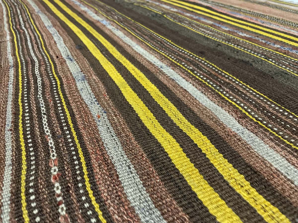 Persian rug of Sumak style in dimensions 141 centimeters length by 117 centimeters width with mainly yellow and brown colors — Texture close-up