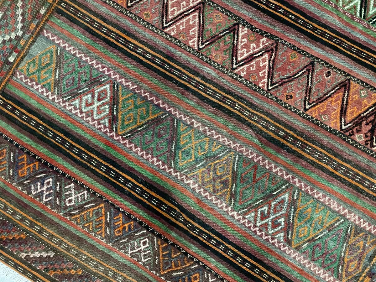 Persian rug of Sumak style in dimensions 155 centimeters length by 135 centimeters width with mainly green and brown colors — Texture close-up