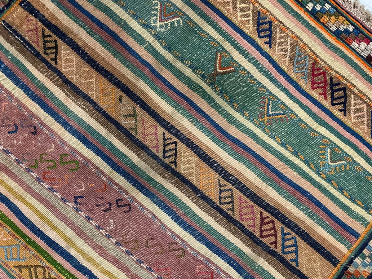Persian rug of Sumak style in dimensions 128 centimeters length by 120 centimeters width with mainly green and yellow colors — Texture close-up