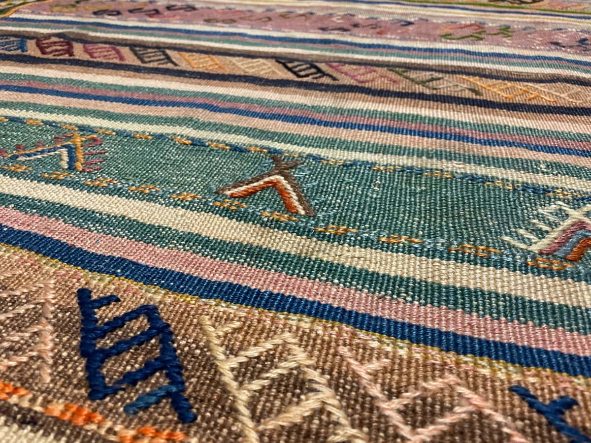 Persian rug of Sumak style in dimensions 128 centimeters length by 120 centimeters width with mainly green and yellow colors — Texture close-up