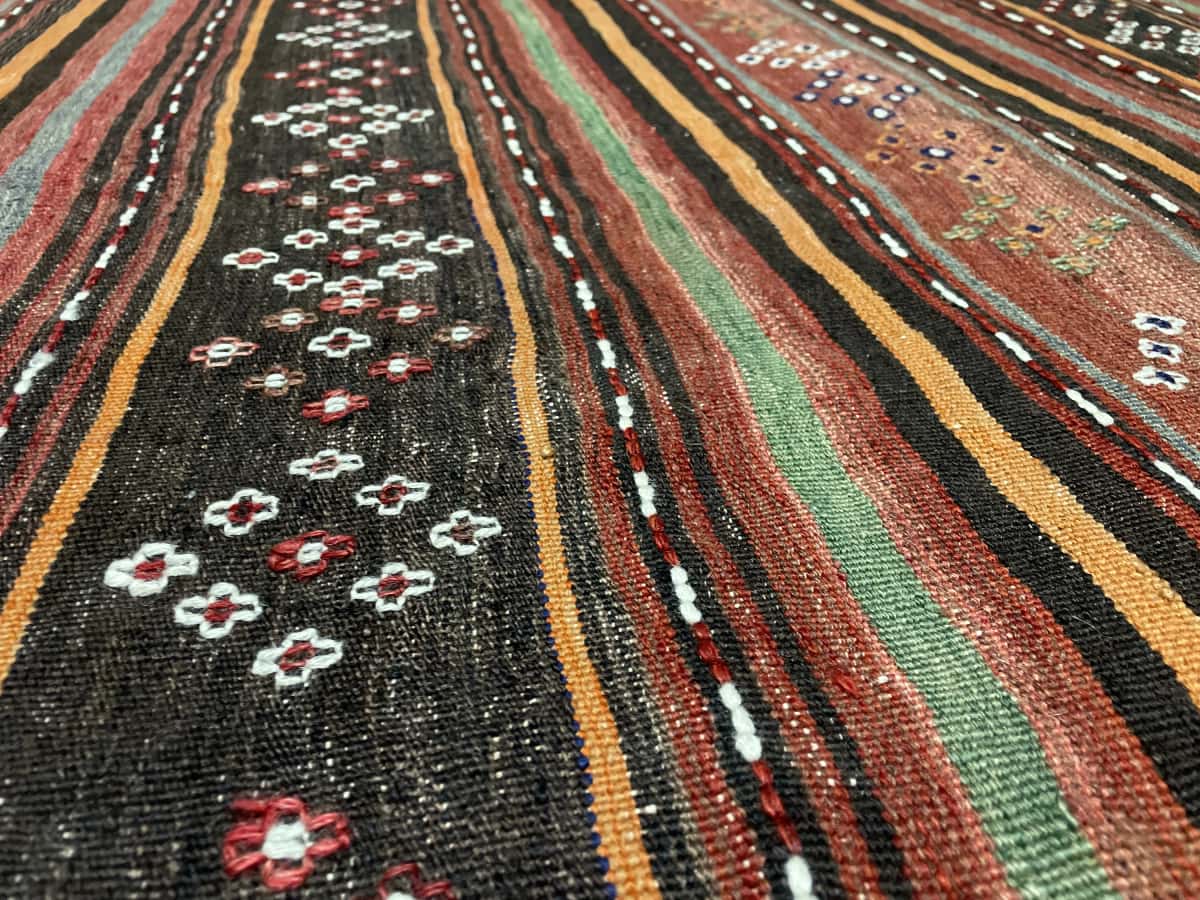 Persian rug of Sumak style in dimensions 125 centimeters length by 120 centimeters width with mainly red and black colors — Texture close-up