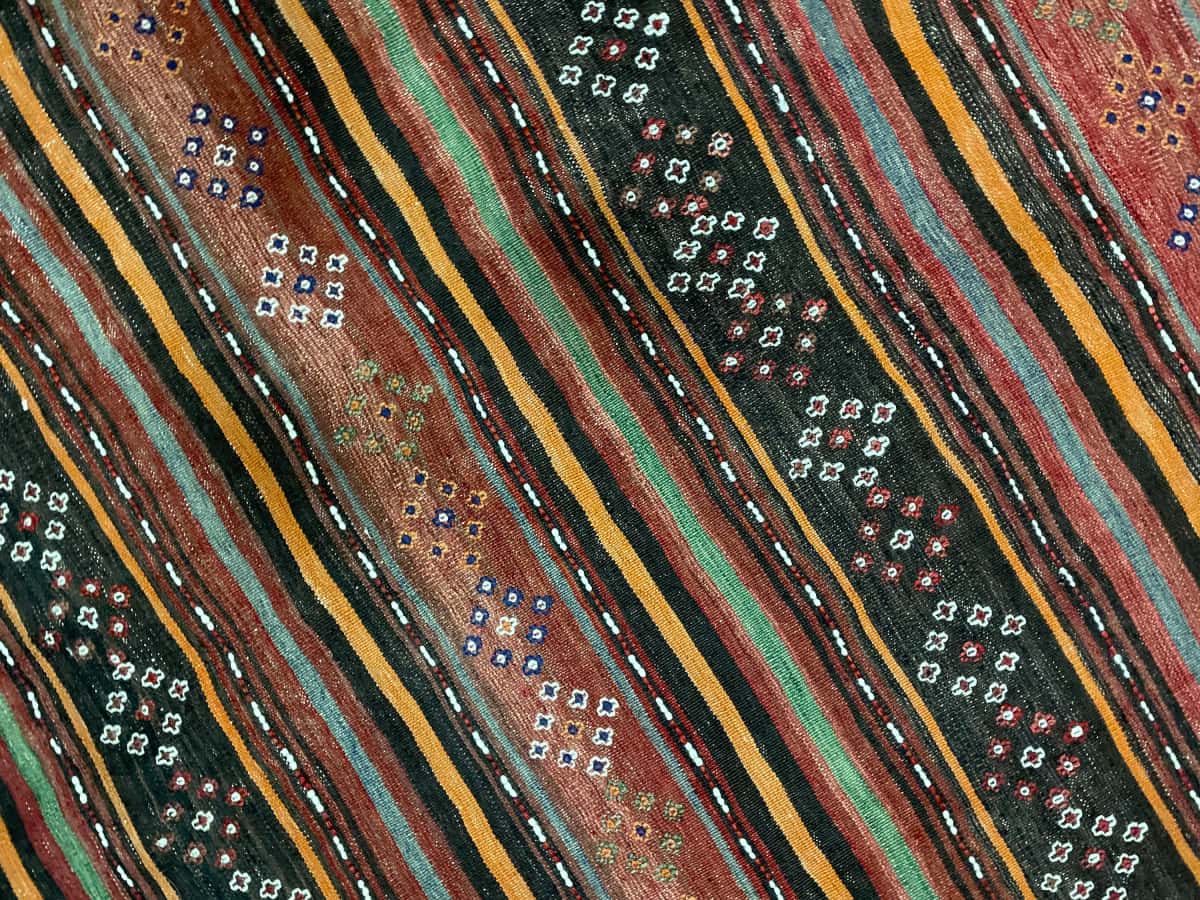 Persian rug of Sumak style in dimensions 125 centimeters length by 120 centimeters width with mainly red and black colors — Texture close-up
