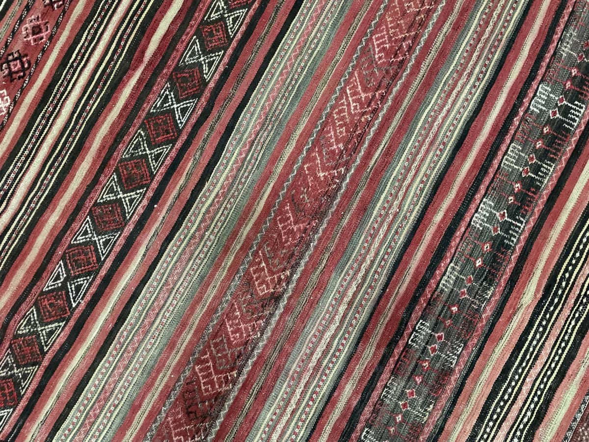 Persian rug of Sumak style in dimensions 165 centimeters length by 154 centimeters width with mainly red colors — Texture close-up