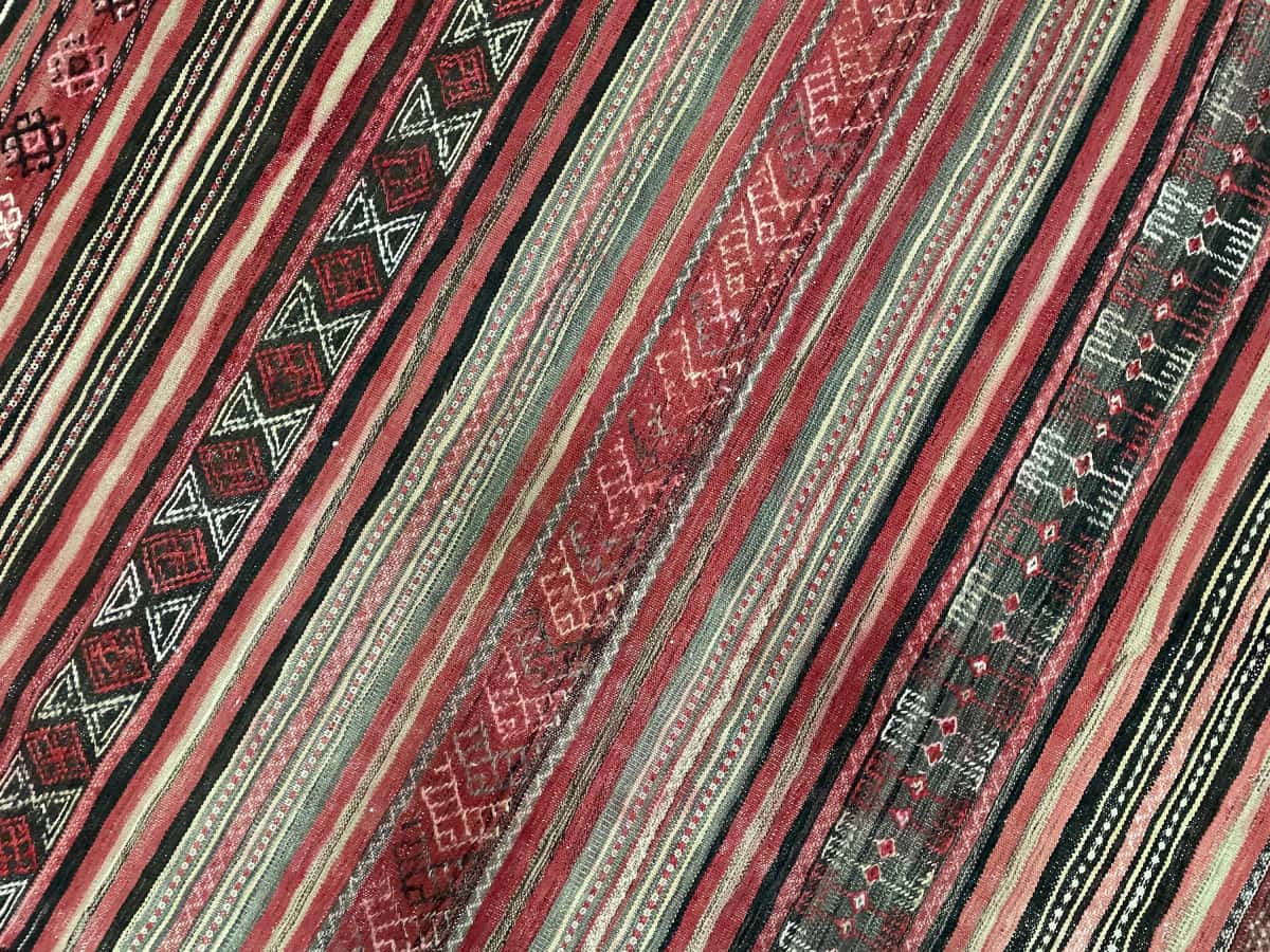 Persian rug of Sumak style in dimensions 165 centimeters length by 154 centimeters width with mainly red colors — Texture close-up