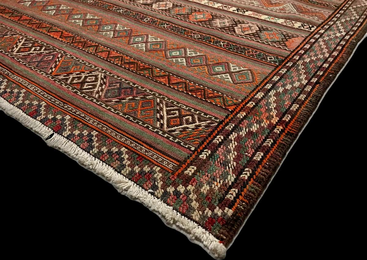 persischer Teppich im Sumak Stil in den Maßen 247 Zentimeter Länge mal 160 Zentimeter Breite mit überwiegend rot und braun Farben — Ecke & Kante
