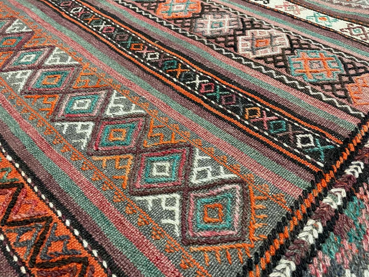 persischer Teppich im Kelim-Sumak Stil in den Maßen 247 Zentimeter Länge mal 160 Zentimeter Breite mit überwiegend Rot und Braun Farben — Nahaufnahme der Textur