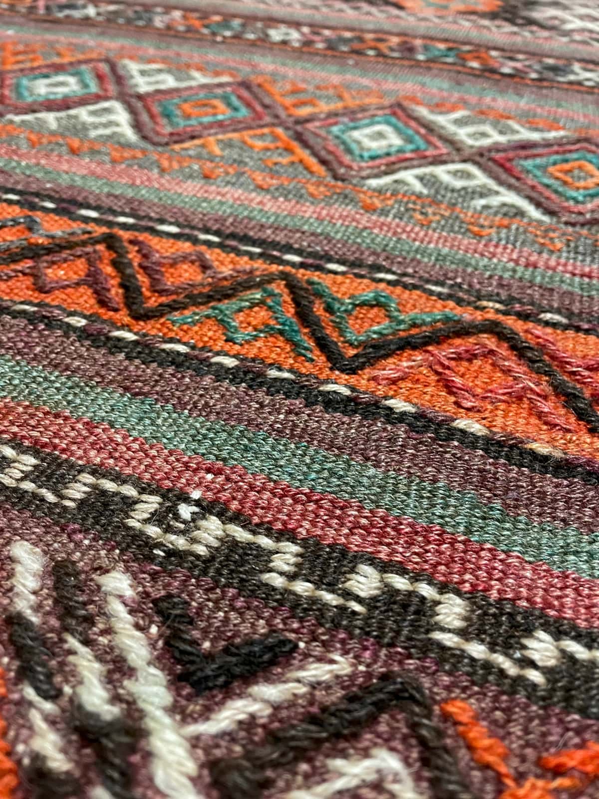 persischer Teppich im Kelim-Sumak Stil in den Maßen 247 Zentimeter Länge mal 160 Zentimeter Breite mit überwiegend Rot und Braun Farben — Nahaufnahme der Textur