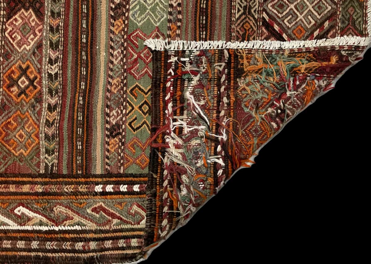 alfombra persa de estilo sumak en dimensiones 154 centímetros de largo por 148 centímetros de ancho con colores principalmente verde y naranja — Plegada