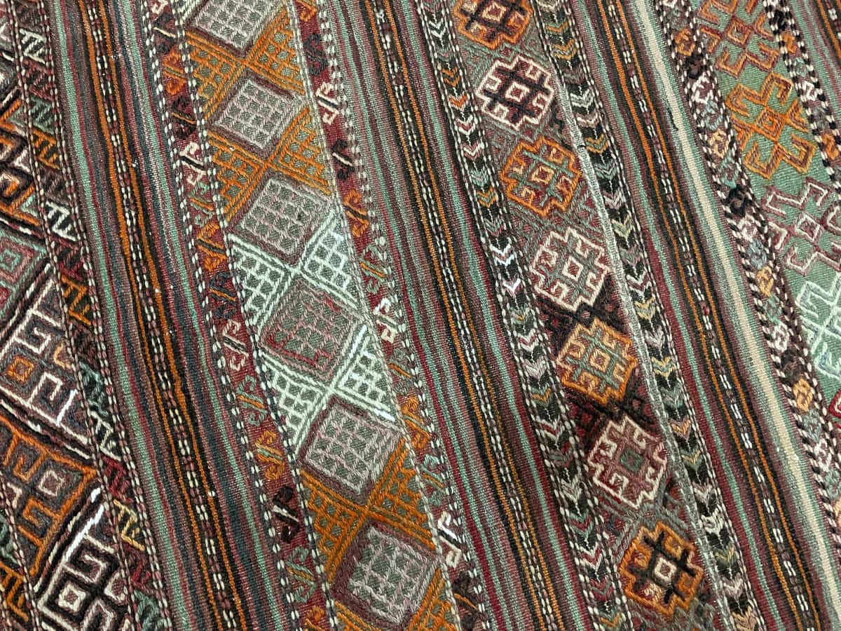alfombra persa de estilo sumak en dimensiones 154 centímetros de largo por 148 centímetros de ancho con colores principalmente verde y naranja — Primer plano de la textura